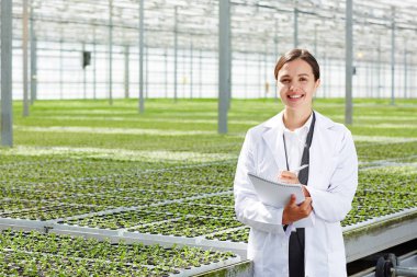 Mutlu genç agro-mühendisi olarak çalışma notları yaparken kameraya bakarak whitecoat