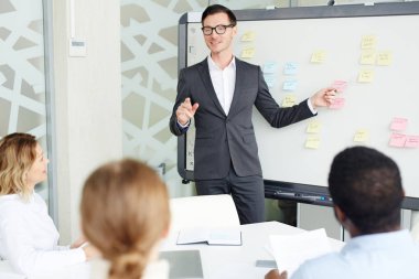 Beyaz tahta işaret ve meslektaşları brifing için yeni iş eğilimleri açıklayan zarif işadamı