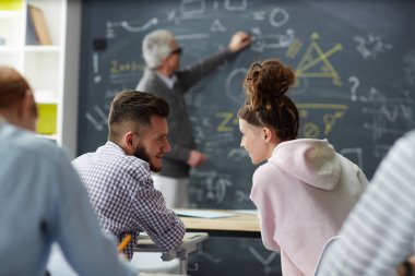 İki öğrenci bir şeyden ders öğretmen tahtaya konuyu açıklayan iken, söz