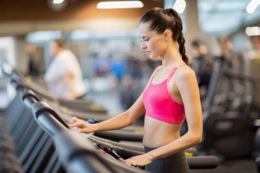 Spor salonunda koşu bandı üzerinde çalışmaya giderken ekranda çalışma hızı seçmeyi giyim uygun kız