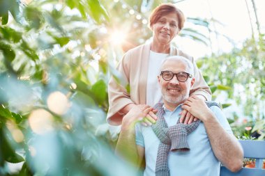 Neşeli ve sevimli yaşlılar orangery veya bahçe yeşil bitkiler arasında vakit gündelik giysiler içinde