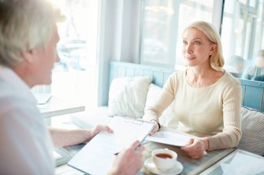 Cafe masa başına oturmuş ve belgeler veya sözleşmeler tartışmak olgun finansörler