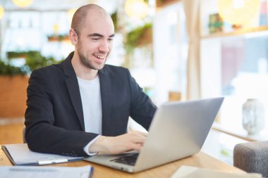 Bilgisayarda sohbet ve gülümseyen genç işadamı