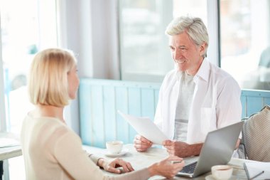 Cafe açılış toplantısı sırasında meslektaşı strateji için dinleme kağıtları ile kendine güvenen ekonomist