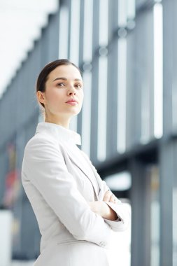 Genç çapraz silahlı lider ya da girişimci şık takım elbise ileri modern binanın içinde arıyor