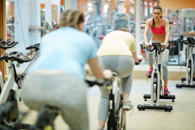 Eğitim sırasında ölçekli kadınlar için Bisiklete binme fitness hakkında öneriler veren genç sportif kız