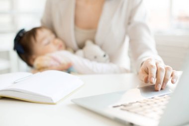 El iş anne sırasında diğer bir uyuyan bebek ile Office ağ dizüstü bilgisayar tuş takımındaki
