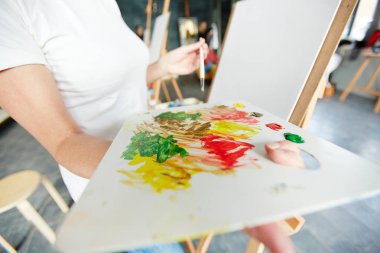 Palet boya ile tutarak ve ders resme önce renkleri karıştırma sanat okulu öğrencisi genç