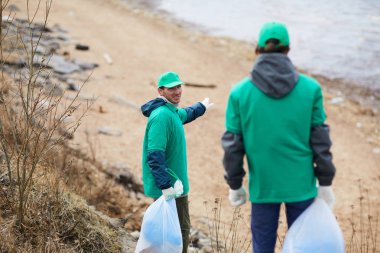 Bir kıyı şeridi işaret ve bu toprakları temizlemek için meslektaşı sunan greenpeacers