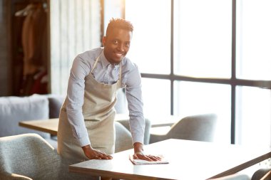 Tek tip sana tablolardan birini kafede silgi ile temizlerken bakmak içinde mutlu garson