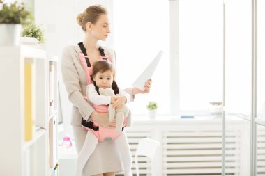 Genç ofis çalışanı ile teddybear oynarken Taşıyıcı bebek kızı ise belgeleri okuma