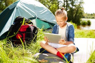 Yaz günü gezi tadını çıkarırken online video izleme tablet ile genç çocuk