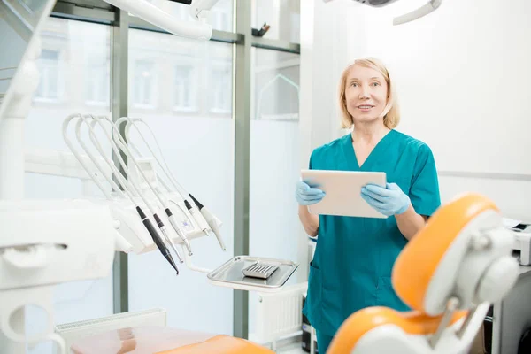 自信的牙医在手套和制服搜寻信息在网在任命新的患者之前 — 图库照片