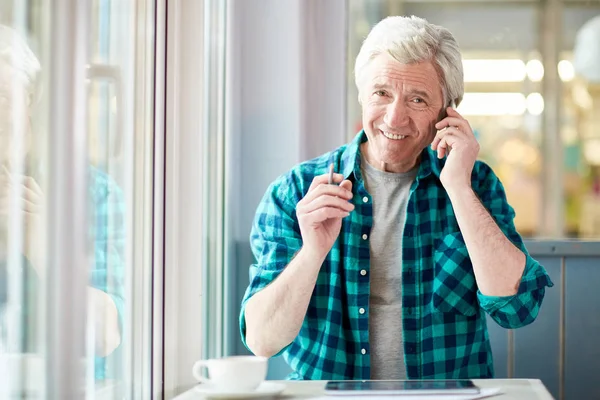 Uśmiechający Się Starszy Człowiek Smartphone Wywołanie Przez Tabela Kawiarni Patrząc — Zdjęcie stockowe