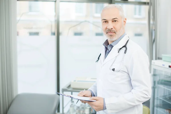 Belge Okunurken Kamera Onun Kliniklerde Bakarak Whitecoat Olgun Doktor — Stok fotoğraf