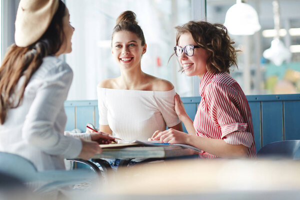Подростковые одногруппники в повседневной одежде проводят перерывы между занятиями в кафе колледжа и беседой.
