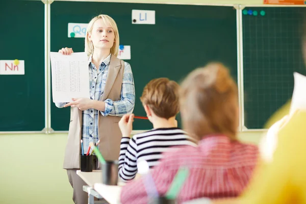 Joven Profesor Confiado Mostrando Papel Con Marcas Términos Clase Estudiantes — Foto de Stock