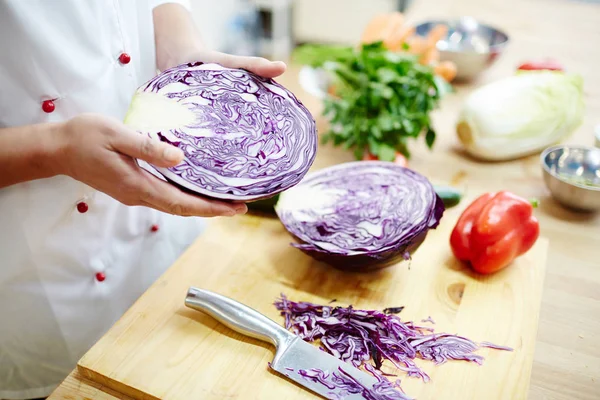 厨师拿着一半新鲜紫甘蓝在桌与其他成分为沙拉 当烹调时 — 图库照片