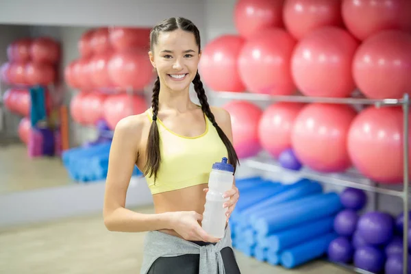 适合微笑的女孩与两个辫子持有塑料瓶与水 而在锻炼之间的休息 — 图库照片