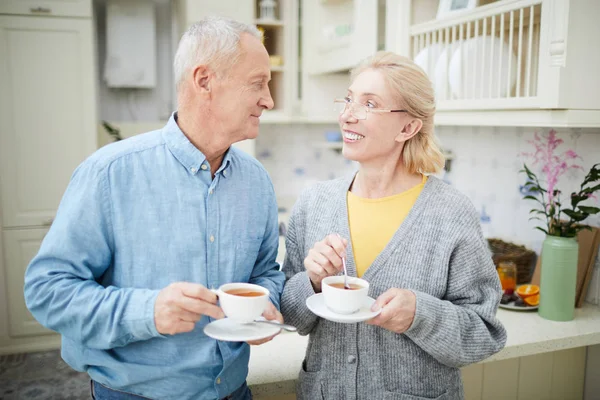 Feliz Pareja Pensionistas Sosteniendo Tazas Mirándose Discutiendo Noticias Cocina — Foto de Stock