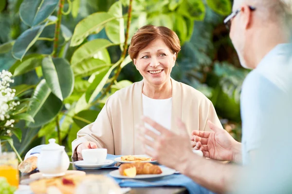 快乐的老年女性和她的丈夫在他们的家庭花园或橘园的早餐交谈 — 图库照片