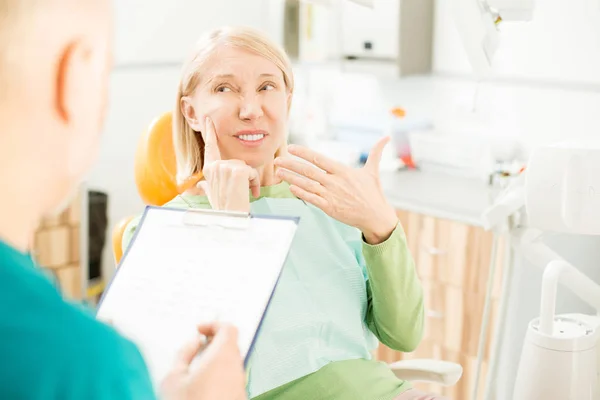 中高年の患者が歯科医との面談中に上の歯の痛みを訴えて — ストック写真