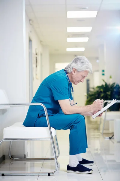 Krankenpfleger Macht Sich Notizen Dokument Während Flur Sitzt — Stockfoto