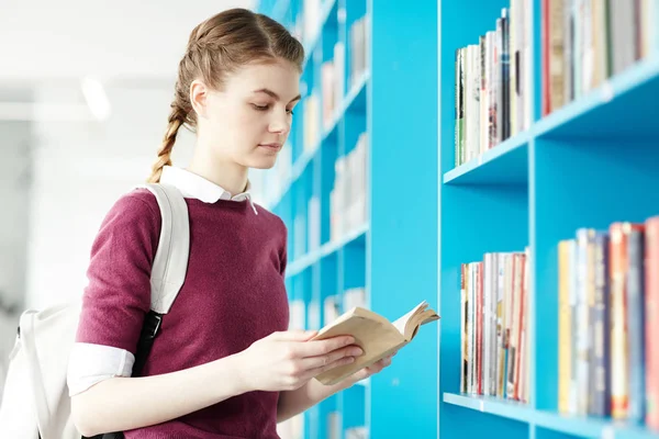 Studente Intelligente Con Zaino Guardando Attraverso Libro Mentre Piedi Scaffale — Foto Stock