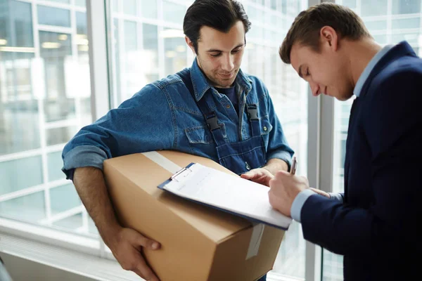 Zakenman Ondertekening Papier Terwijl Ontvangt Pakket Met Kantoorbenodigdheden Courier — Stockfoto