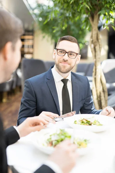 レストランでの昼食時に彼に話している間彼のビジネス パートナーを見てエレガントなスーツを着た若い男 — ストック写真