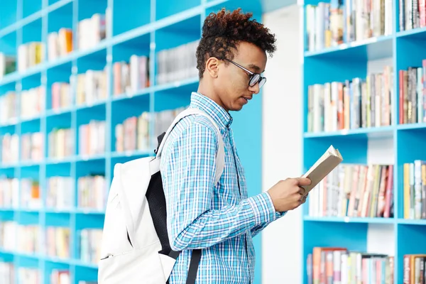 Adolescente Moderno Que Concentra Leer Libro Mientras Visita Biblioteca Universitaria — Foto de Stock