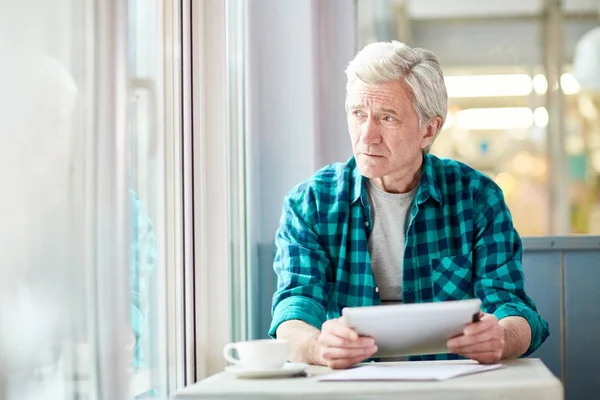 Fundersam Senior Mannen Med Tablett Tittar Genom Fönstret Café Samtidigt — Stockfoto