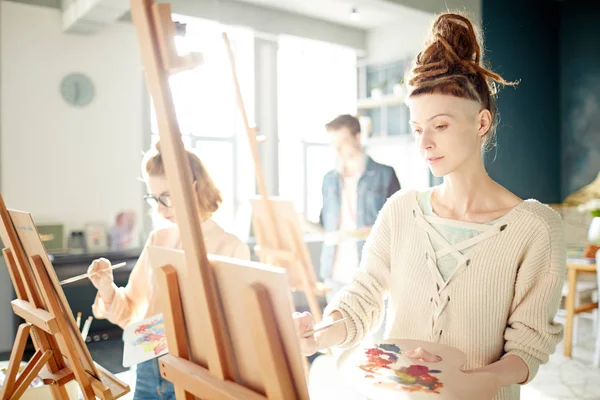美術学校で絵を描くイーゼルの背景に彼女のれば若い才能のある学生 — ストック写真