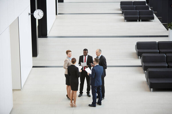 Круг элегантных бизнесменов или делегатов в формальной одежде, говорящих о финансовых ставках
