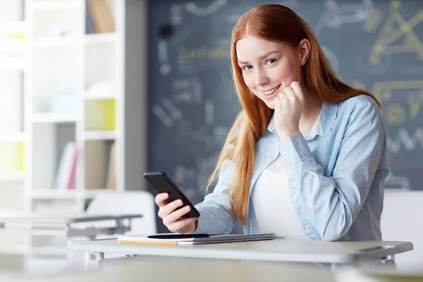 Lächelnde Studentin Blickt Die Kamera Während Sie Mit Smartphone Und — Stockfoto