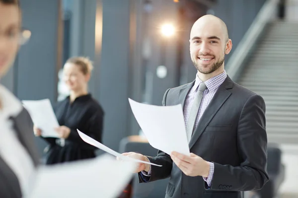 Fröhlicher Finanzier Mit Papieren Die Einen Anschauen Während Sein Team — Stockfoto