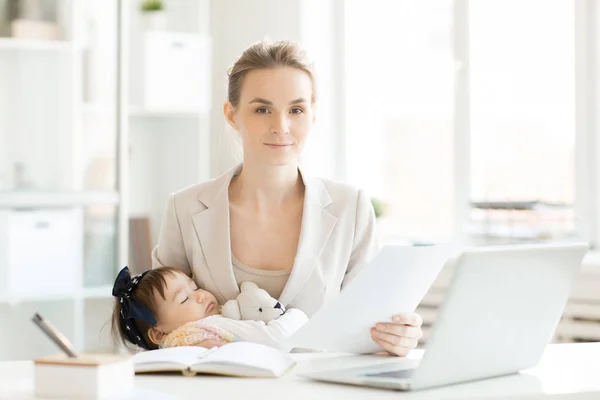 若いエレガントなビジネス論文職場で座って 彼女のかわいい眠っている赤ん坊の娘と母 — ストック写真