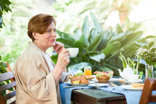 Ανώτερων Γυναίκα Μπεζ Homewear Πίνοντας Τσάι Από Σερβίρεται Τραπέζι Φρέσκα — Φωτογραφία Αρχείου