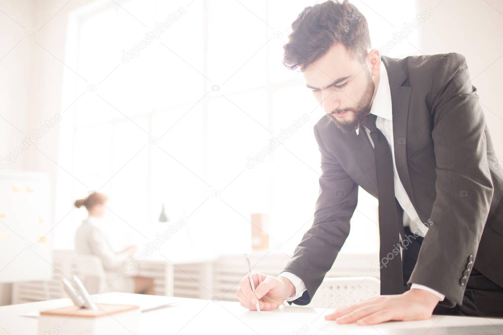 Serious businessman signing a contract at the table