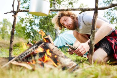 Genç backpacker Woods ormandaki gezisi sırasında kaynar tava altında yanan üfleme