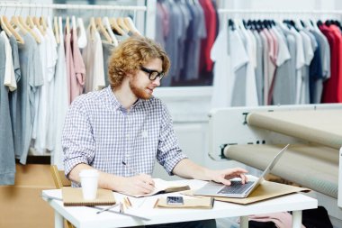 Tasarımcı dizüstü kullanarak ve notlar not defteri masada yapma