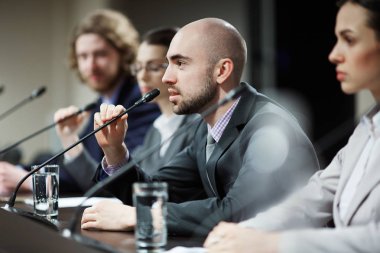 İş veya iş arkadaşları arasında siyasi konferans mikrofon konuşmak genç konuşmacılardan biri