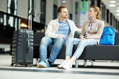 Havaalanı lounge alanında oturup ve uçak için beklerken konuşmayı genç modern çift
