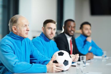 Olgun futbol antrenörü futbol topu ve satır spor Konferansı'nda oturan ekibi ile