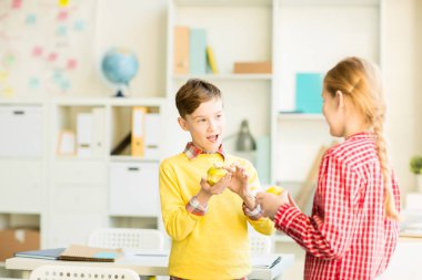 Sevimli küçük öğrenci ile sarı elma öğle yemeği molası sırasında onun sınıf arkadaşı arıyorum