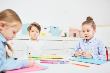 Küçük erkek ve kız resmi kağıt üzerine çizim onların groupmate bakarak