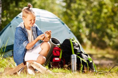 Çadır arka plan üzerinde kahvaltı için bir şeyler pişirmek için maç ateş yakmak çalışıyor ile küçük çocuk