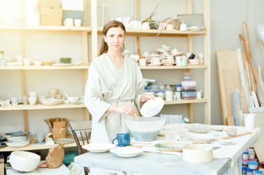 El sanatları stüdyosunda çalışırken özel plastik kabın içinde sıvı kil karıştırma plaka ile genç kadın