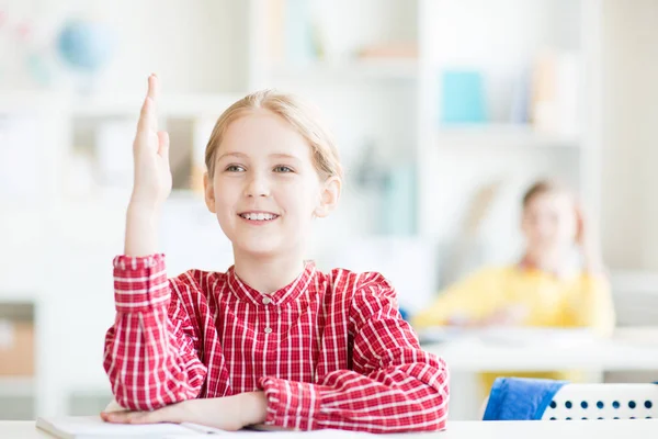 Uczennica Uśmiech Zębiczny Podnosząc Jej Rękę Siedząc Przy Biurku Lekcji — Zdjęcie stockowe