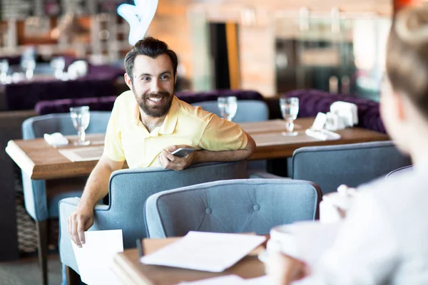 Empresário Feliz Com Smartphone Olhando Para Seu Colega Enquanto Sentado — Fotografia de Stock